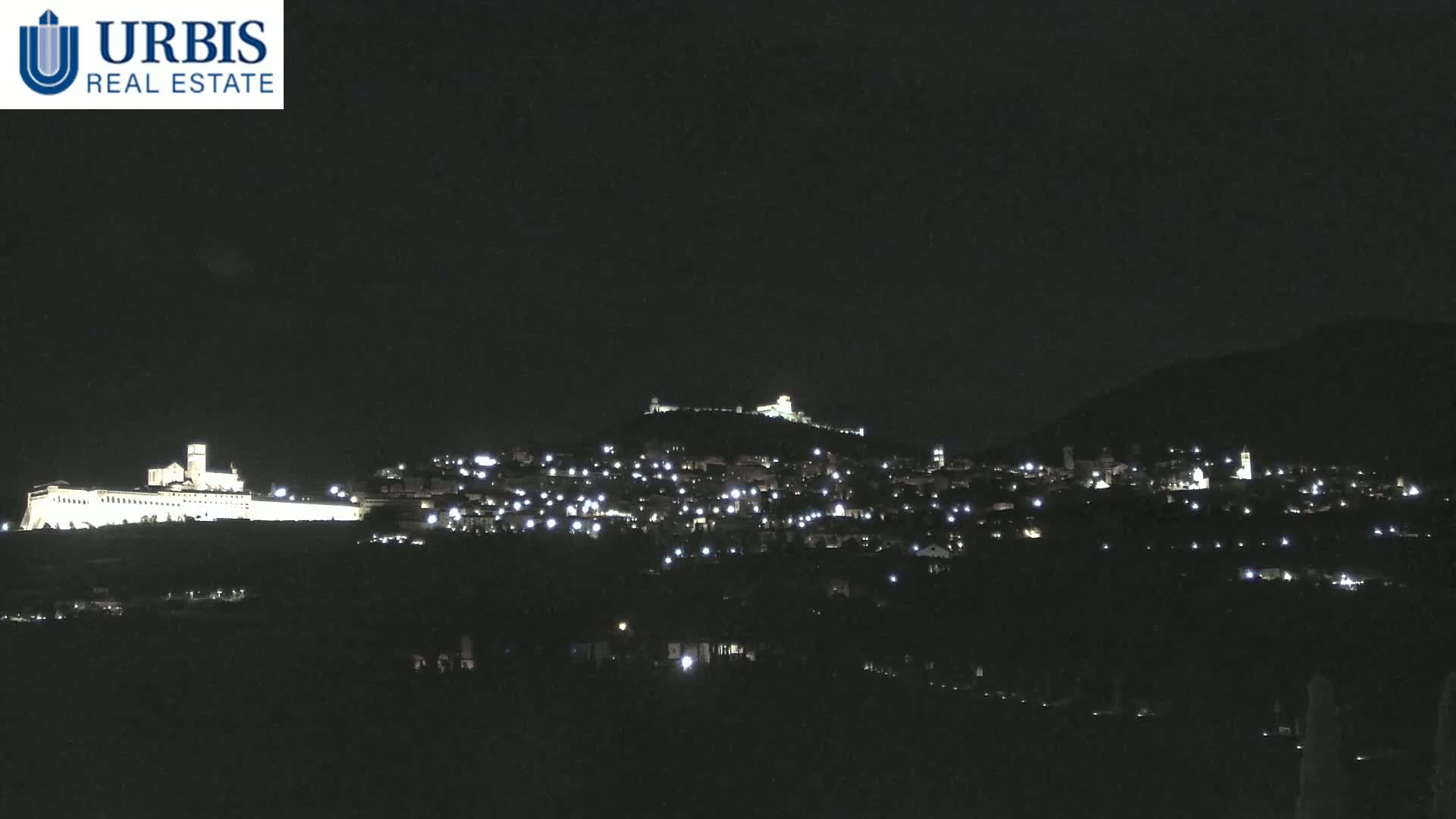 A nighttime view of a town and a large building, illuminated against a dark sky.