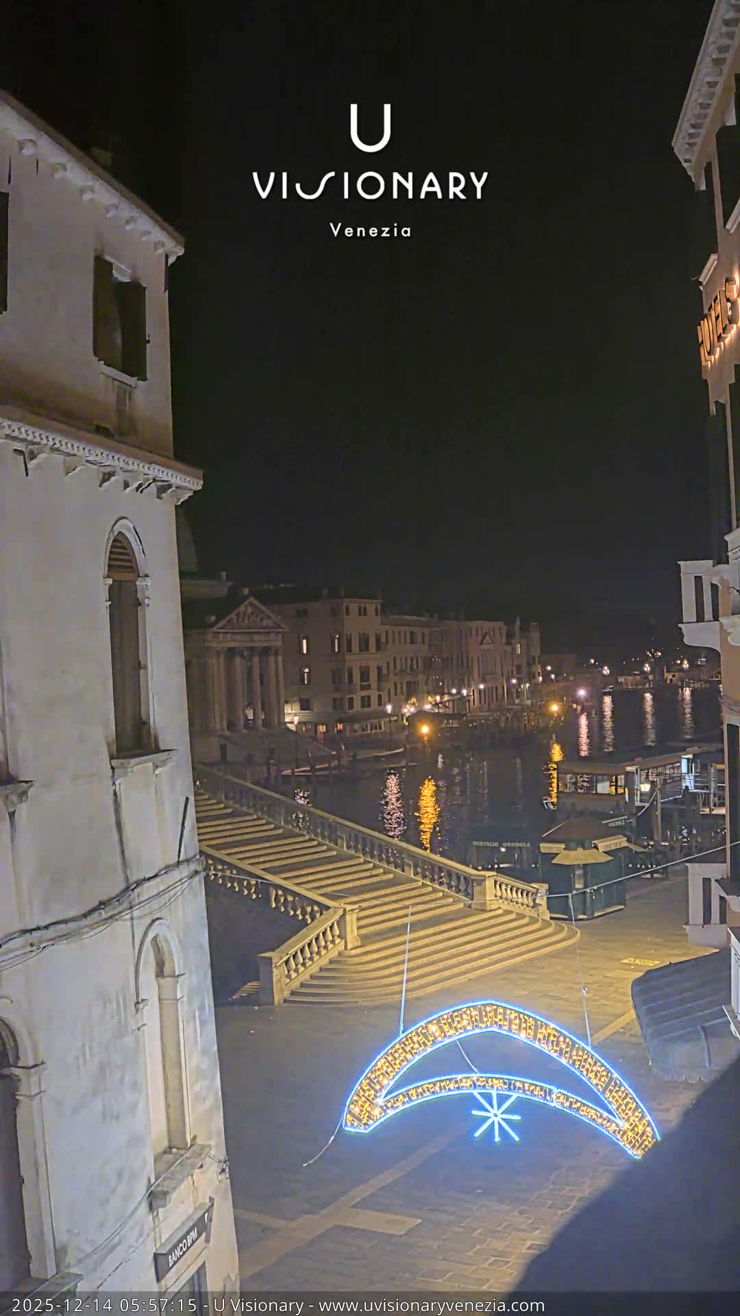 An overcast day hangs over a European town square featuring a prominent cathedral, surrounding buildings, and a festive market area decorated with stalls and a large wooden tree-like structure.