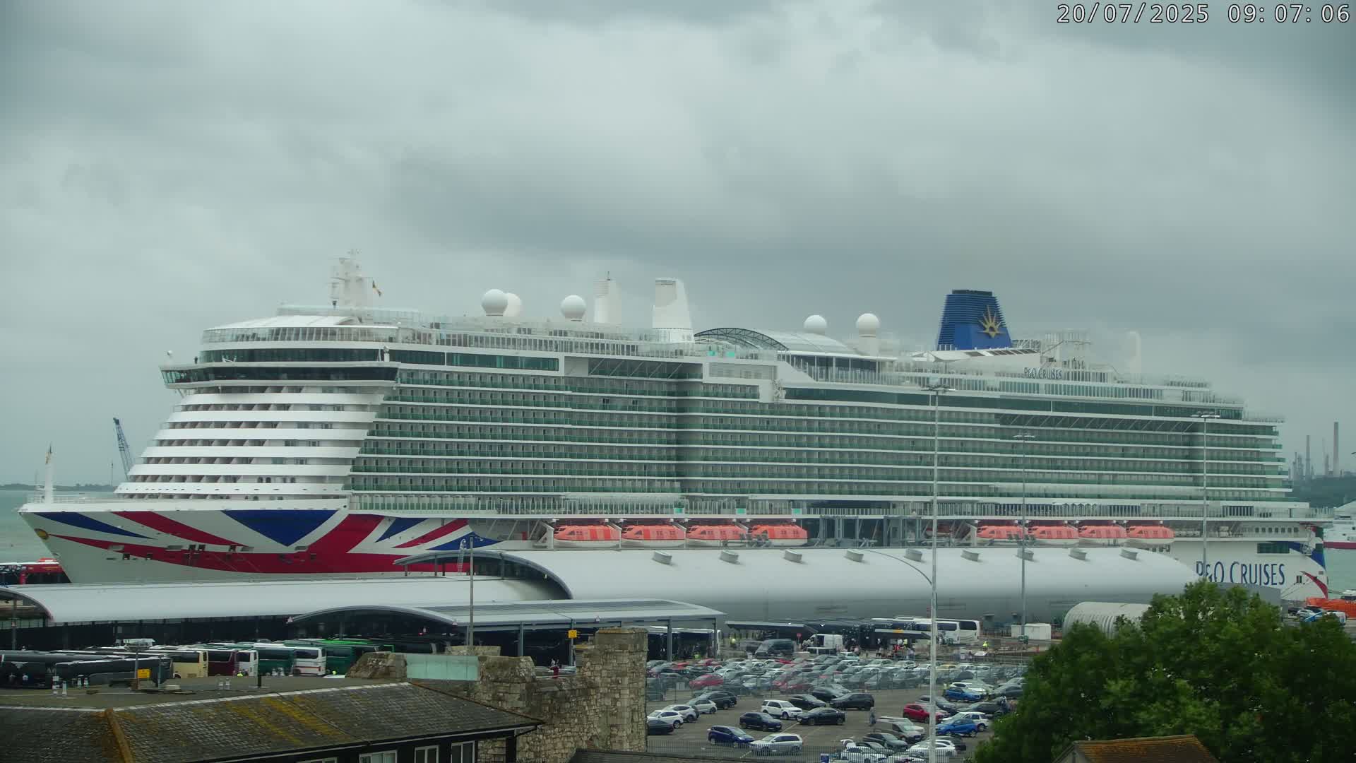 A large cruise ship is docked at a port under a cloudy sky.