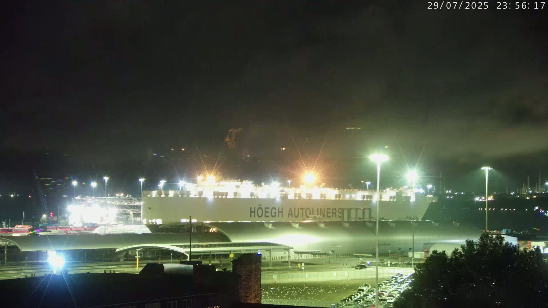 A large cruise ship is docked at a port under a cloudy sky.