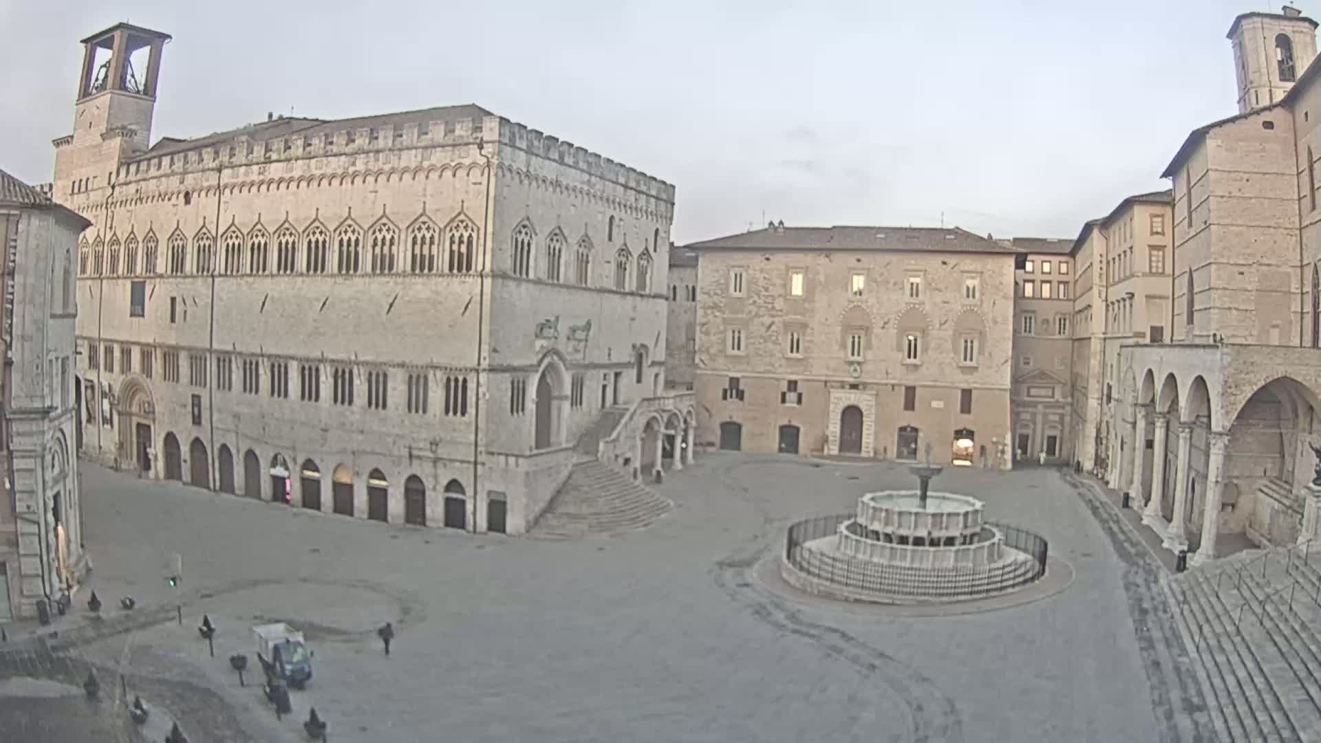 A large, empty town square with several stone buildings, including a large palace and a church, is visible under an overcast sky.