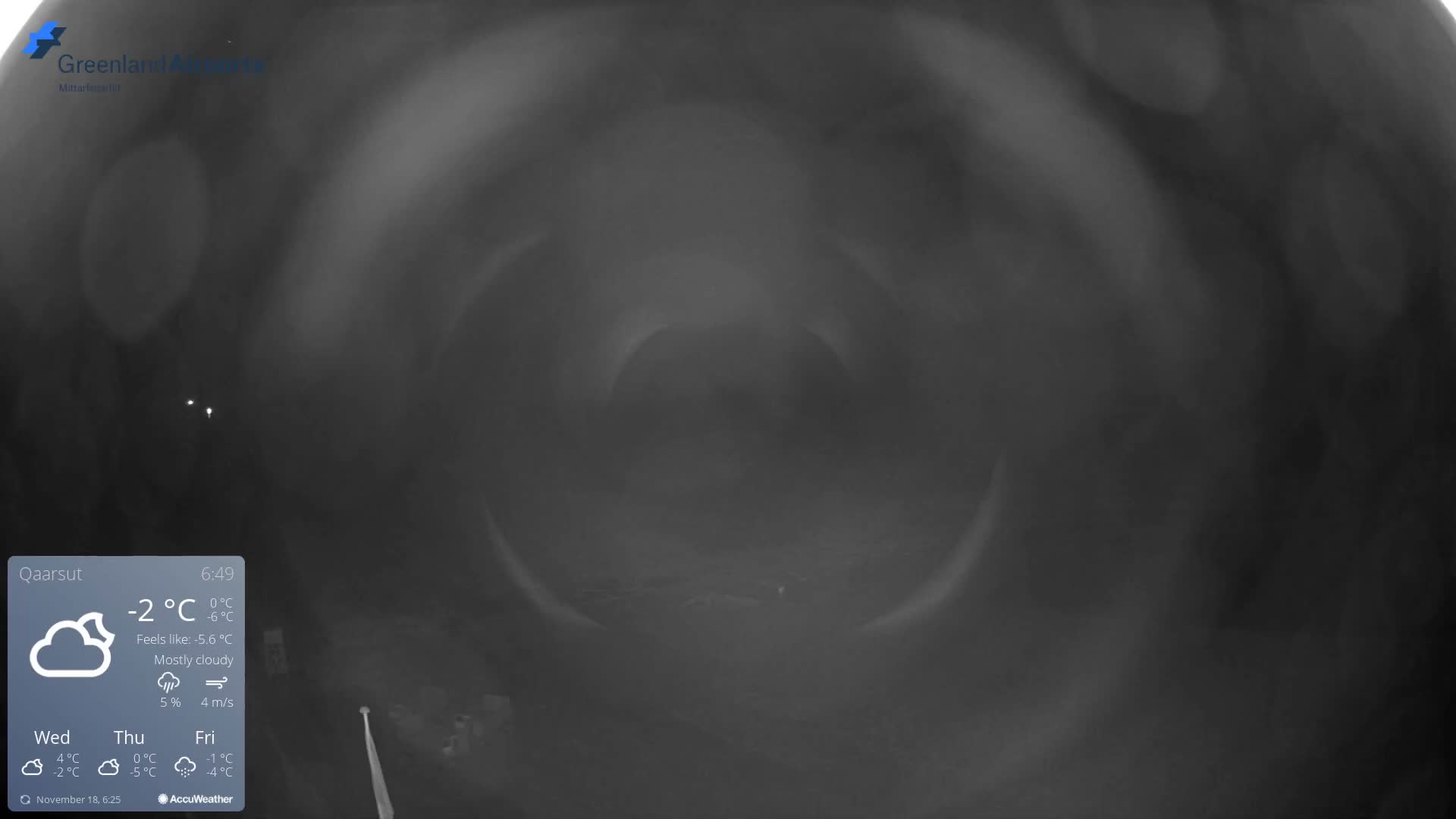 The image displays a dark, heavily distorted outdoor scene obscured by extreme haze or fog, resulting in very poor visibility with only faint distant lights discernible.