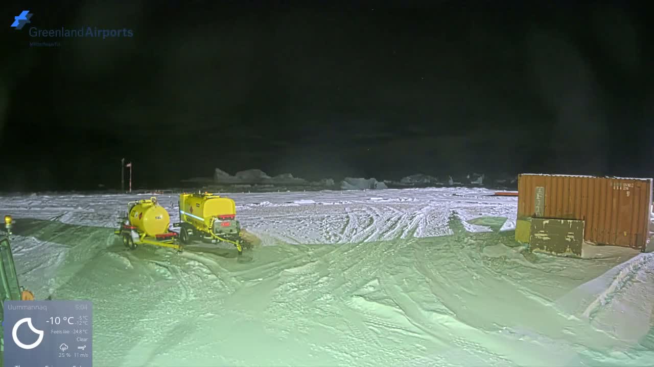 A clear, cold, snowy night reveals two yellow tanker trailers and a brown shipping container on a snow-covered field, with distant ice formations visible under a dark sky.