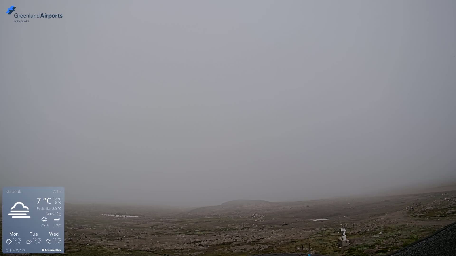 A flat, rocky landscape is shrouded in dense fog under a gray sky.