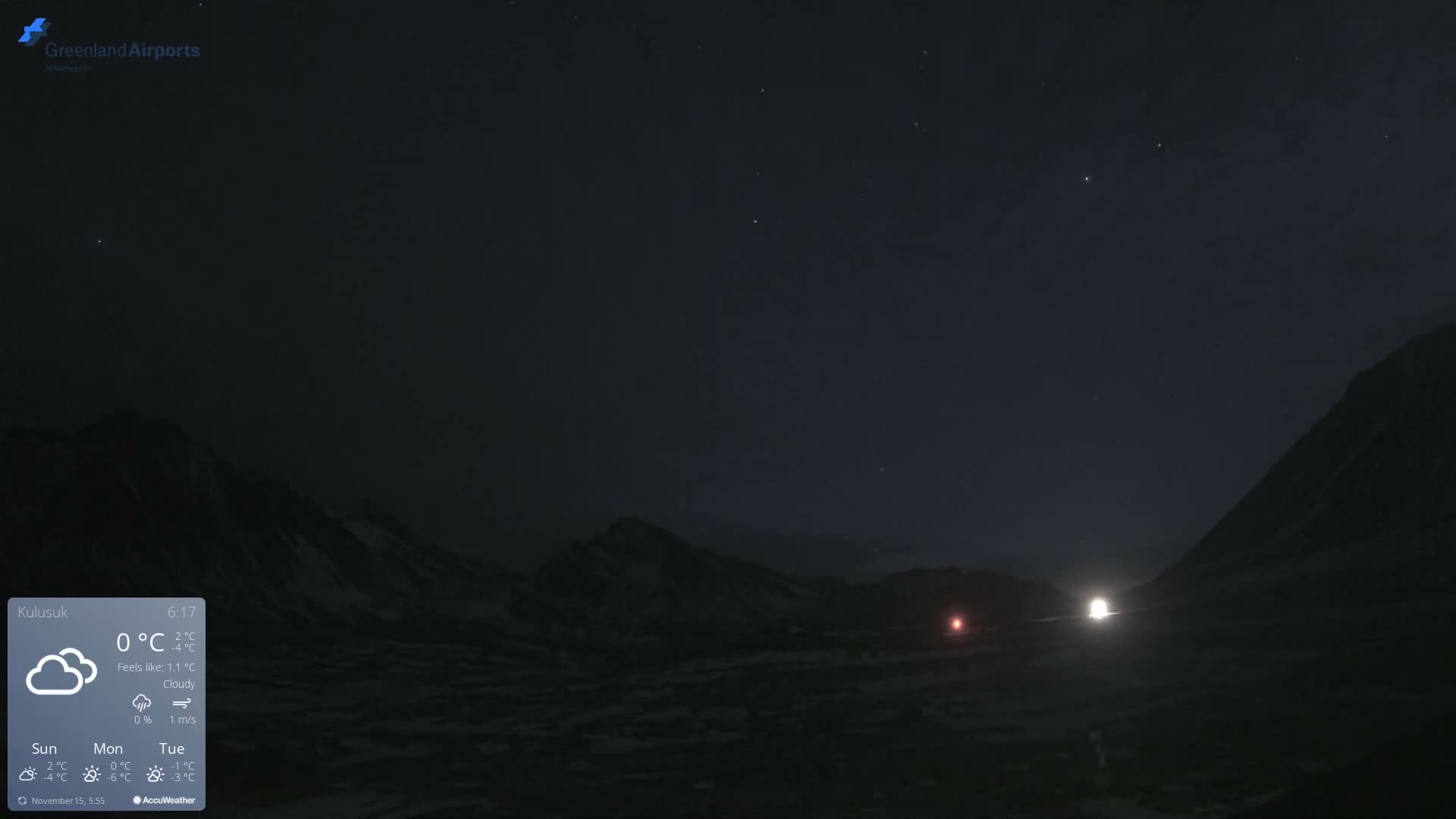 A vast, dark, snow-covered mountainous landscape under a clear, starlit night sky features two distant bright lights, one red and one white.