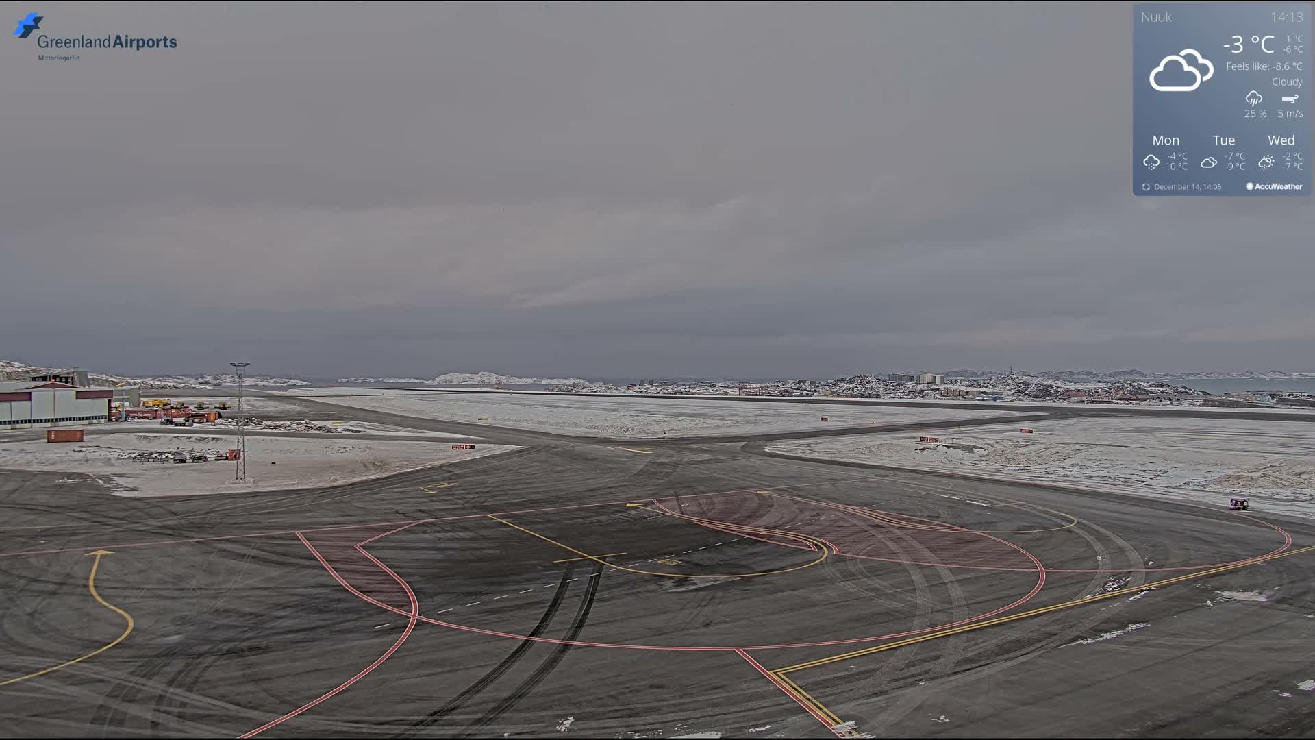 A nighttime view reveals a snow-dusted airport tarmac and runway, illuminated by ground lights with visible vehicle tracks, all under clear and cold weather conditions.