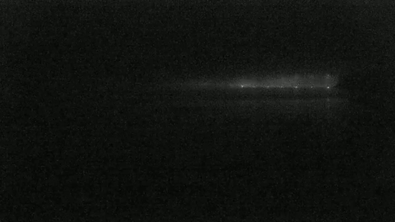 A faint, horizontal streak of light appears across a dark, grainy background.