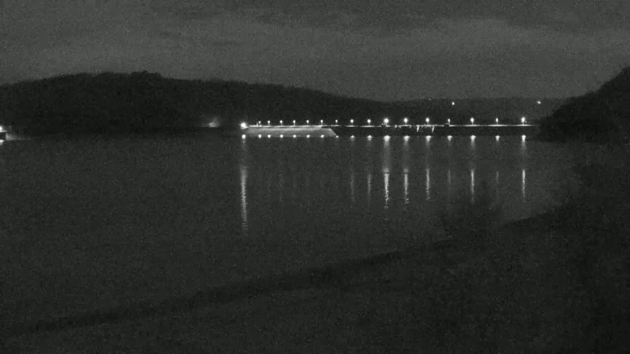 A nighttime view of a dam with lights illuminating the water.