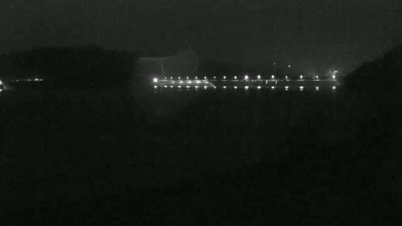 A long line of lights is visible at night across a dark body of water.