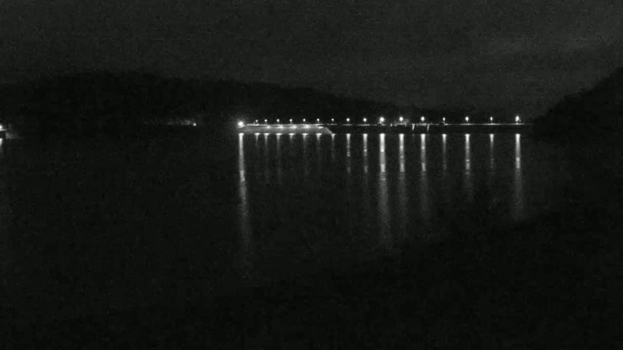 A nighttime view of a body of water reflecting the lights of a structure along its edge.