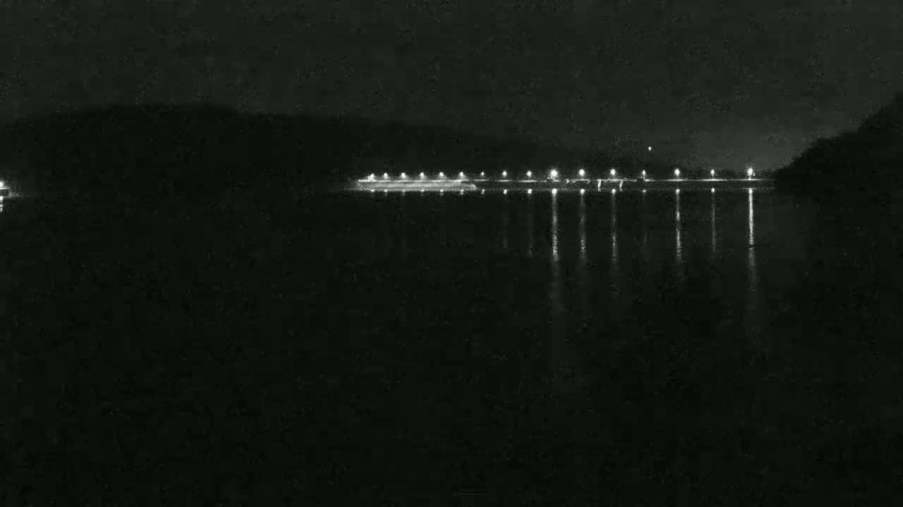 A nighttime view of a calm body of water reflecting the lights of a distant shoreline.