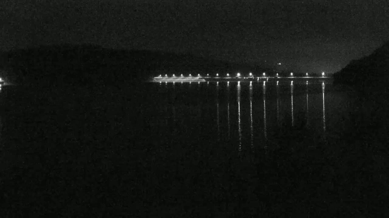 At night, a body of still water reflects the lights of a distant shoreline.