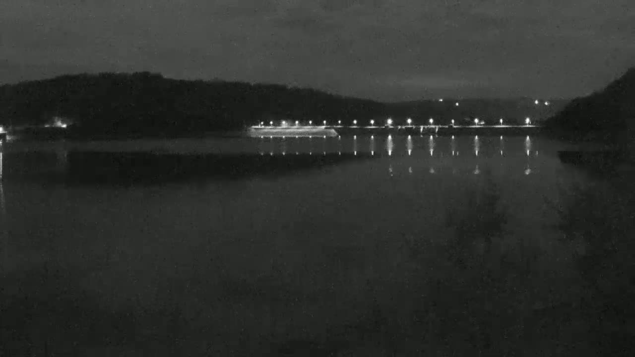 A dark body of water reflects the lights illuminating a distant shoreline at night.