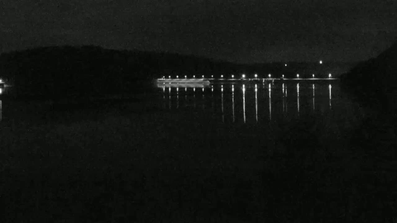 Lights from a structure on the far shore reflect on a dark body of water at night.