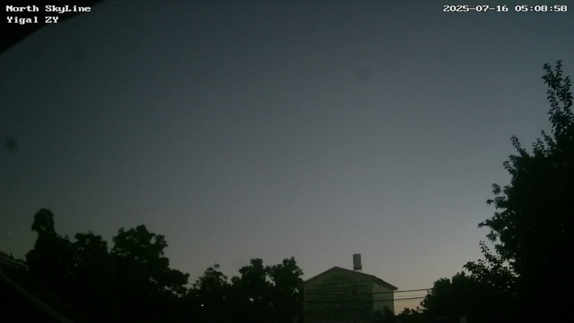 A dark, twilight sky is over a house partially obscured by trees.