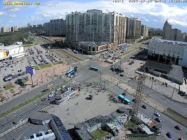 A city intersection with several buildings and vehicles on a sunny day.