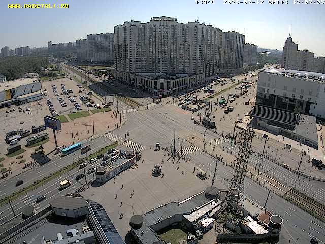 A city intersection with several buildings and vehicles on a sunny day.