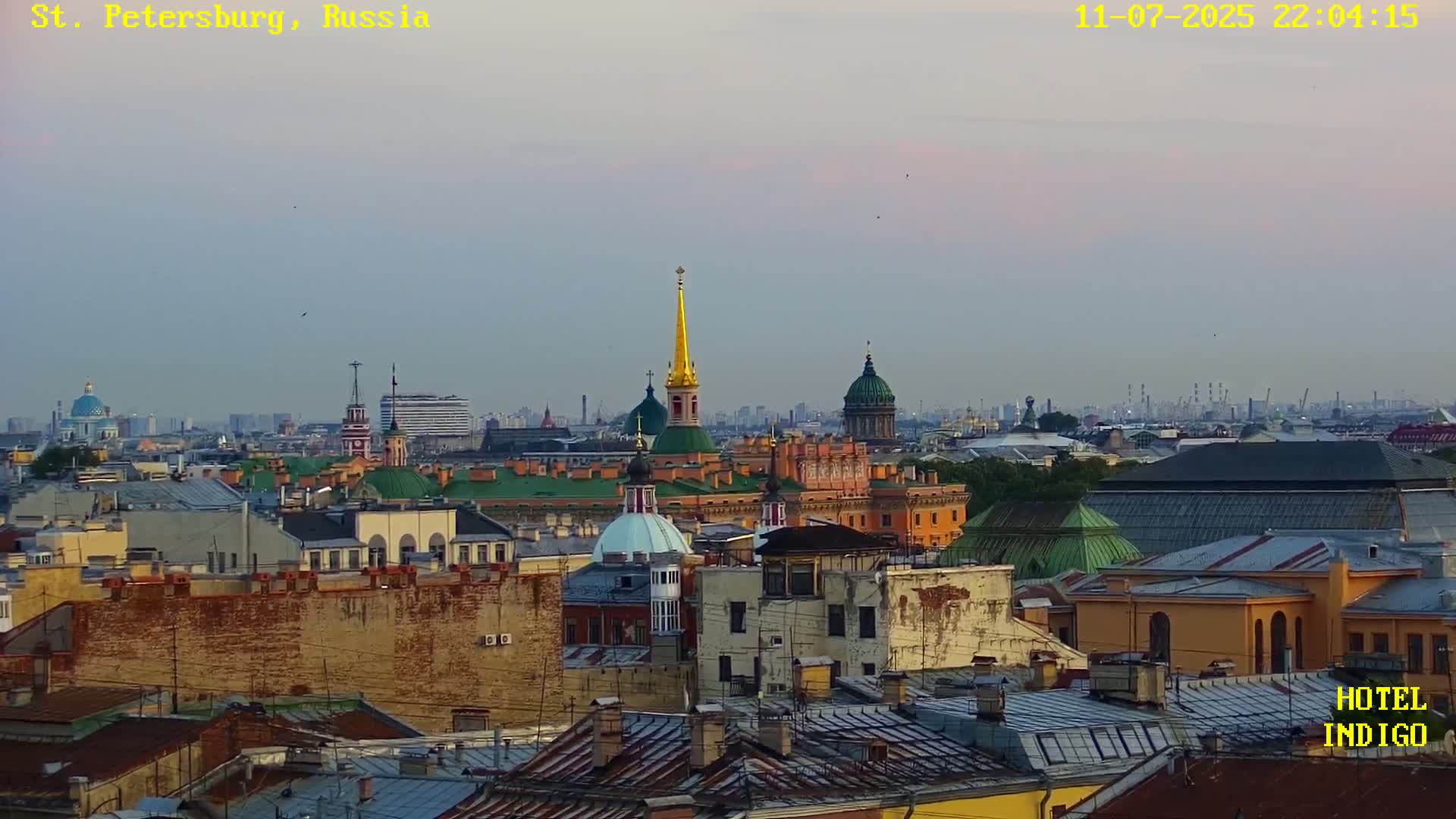 A cityscape with golden-domed churches and a tall spire under a partly cloudy sky.