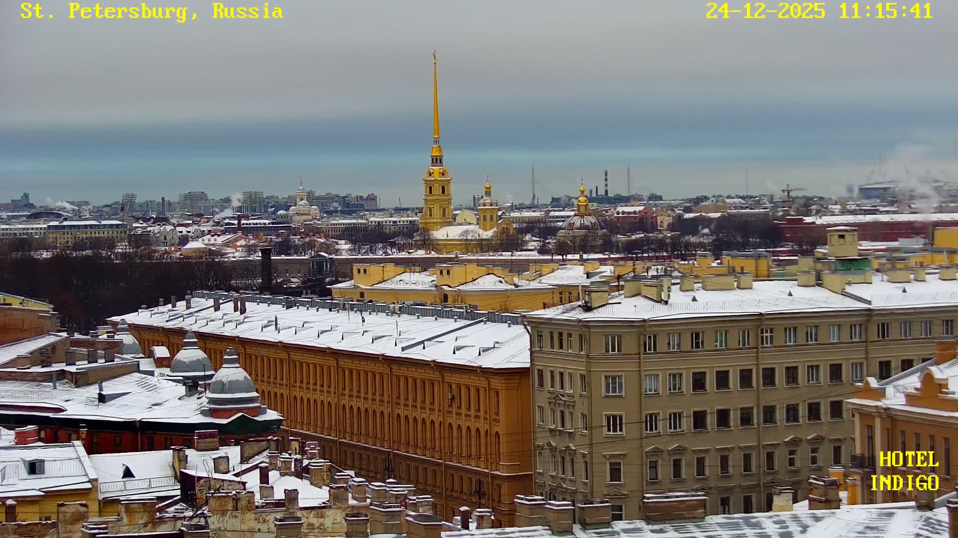 A panoramic winter cityscape displays numerous snow-covered buildings, including a prominent golden-spired cathedral, extending under an overcast sky.