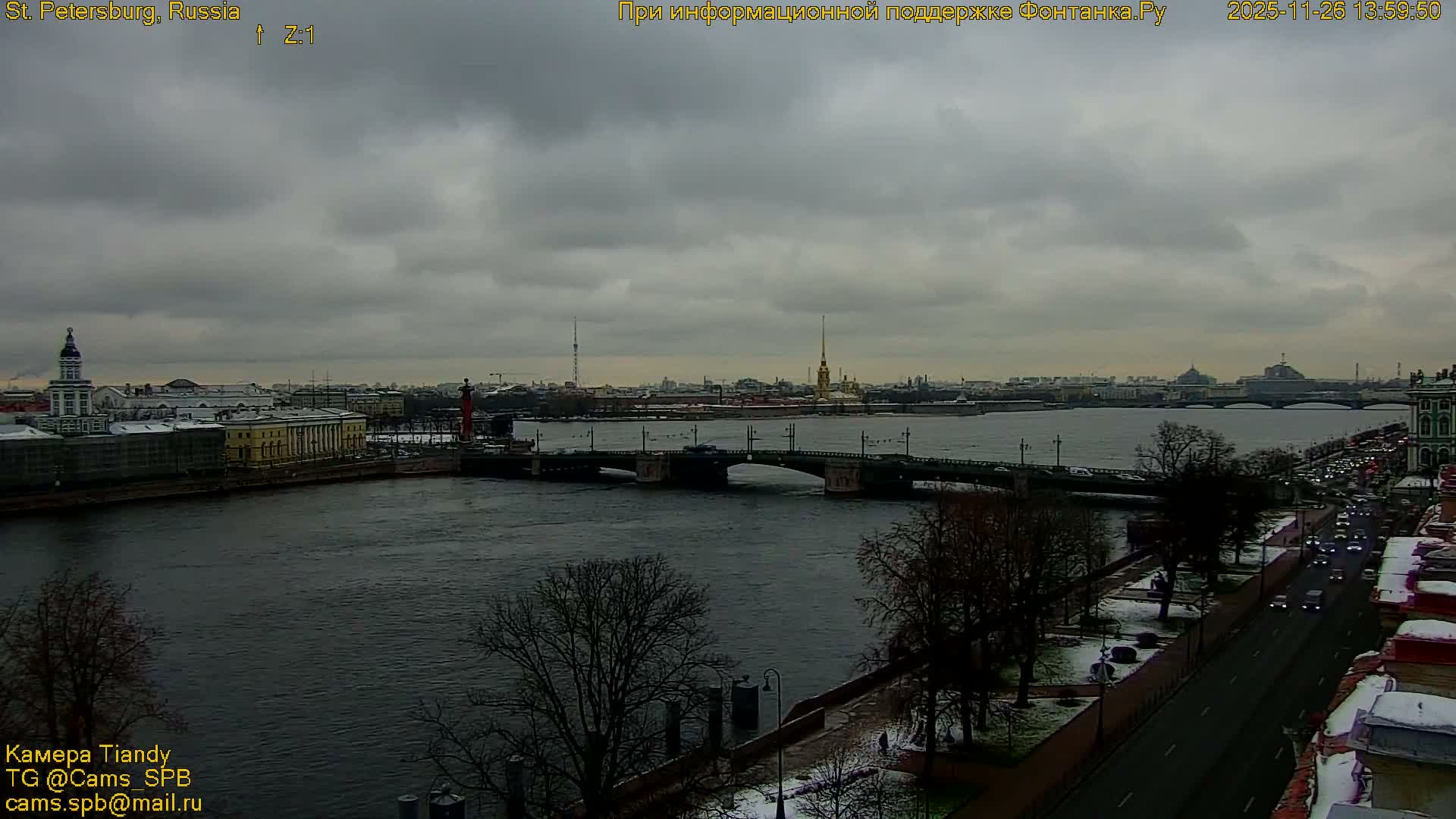 A white, blue, and yellow flag flies on a pole against a predominantly overcast sky with hints of twilight colors, with port cranes just visible on the horizon.