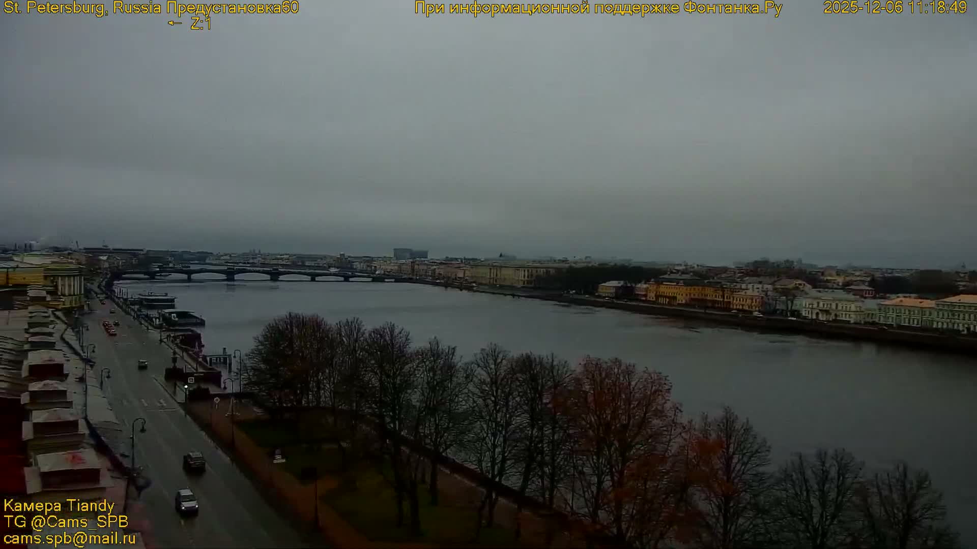The image captures a wide urban river flanked by a road with sparse traffic and buildings, leading to several distant bridges and a cityscape, all beneath a heavily overcast and gloomy sky.