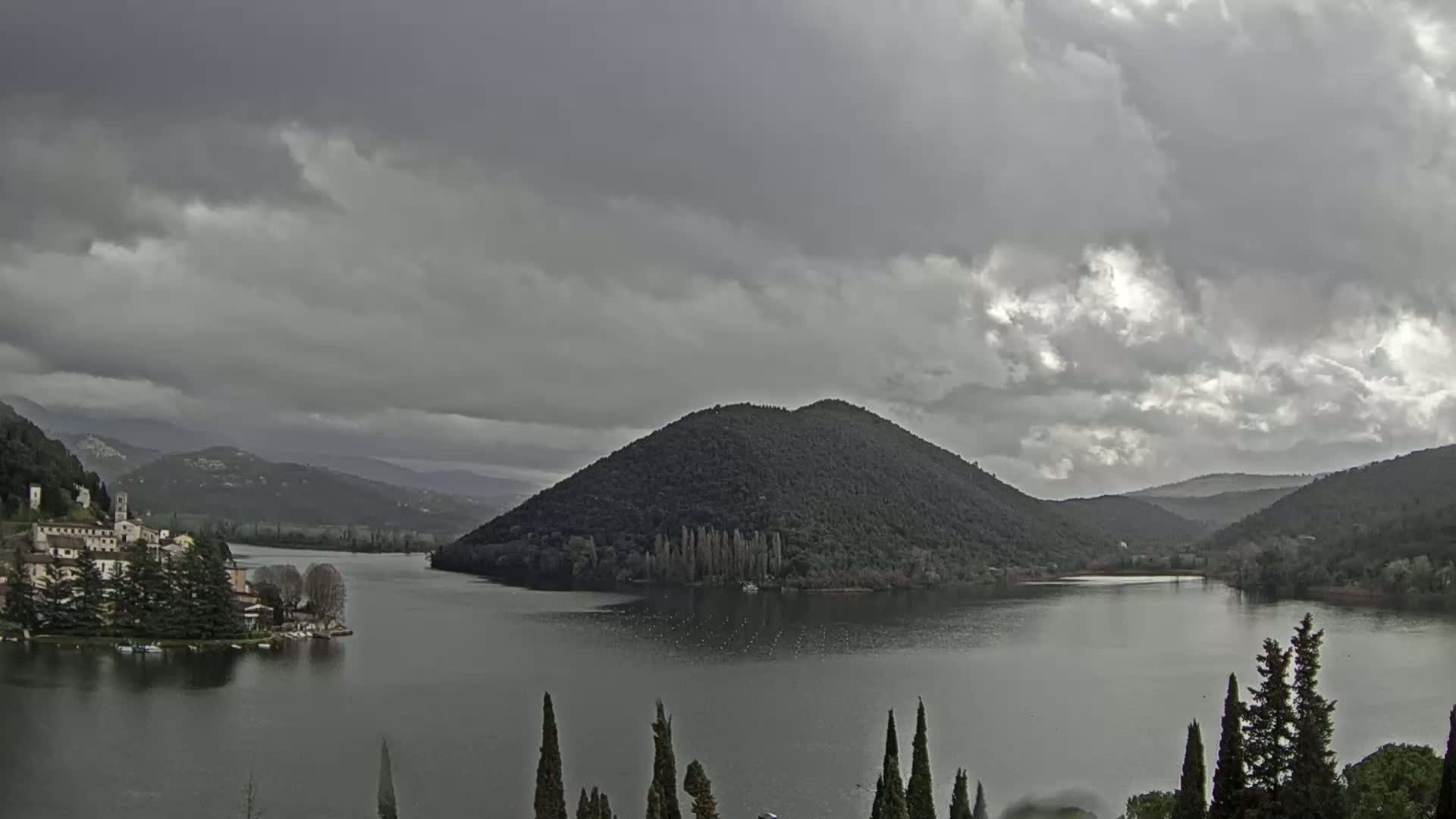 A lake surrounded by mountains and a small village under an overcast sky.