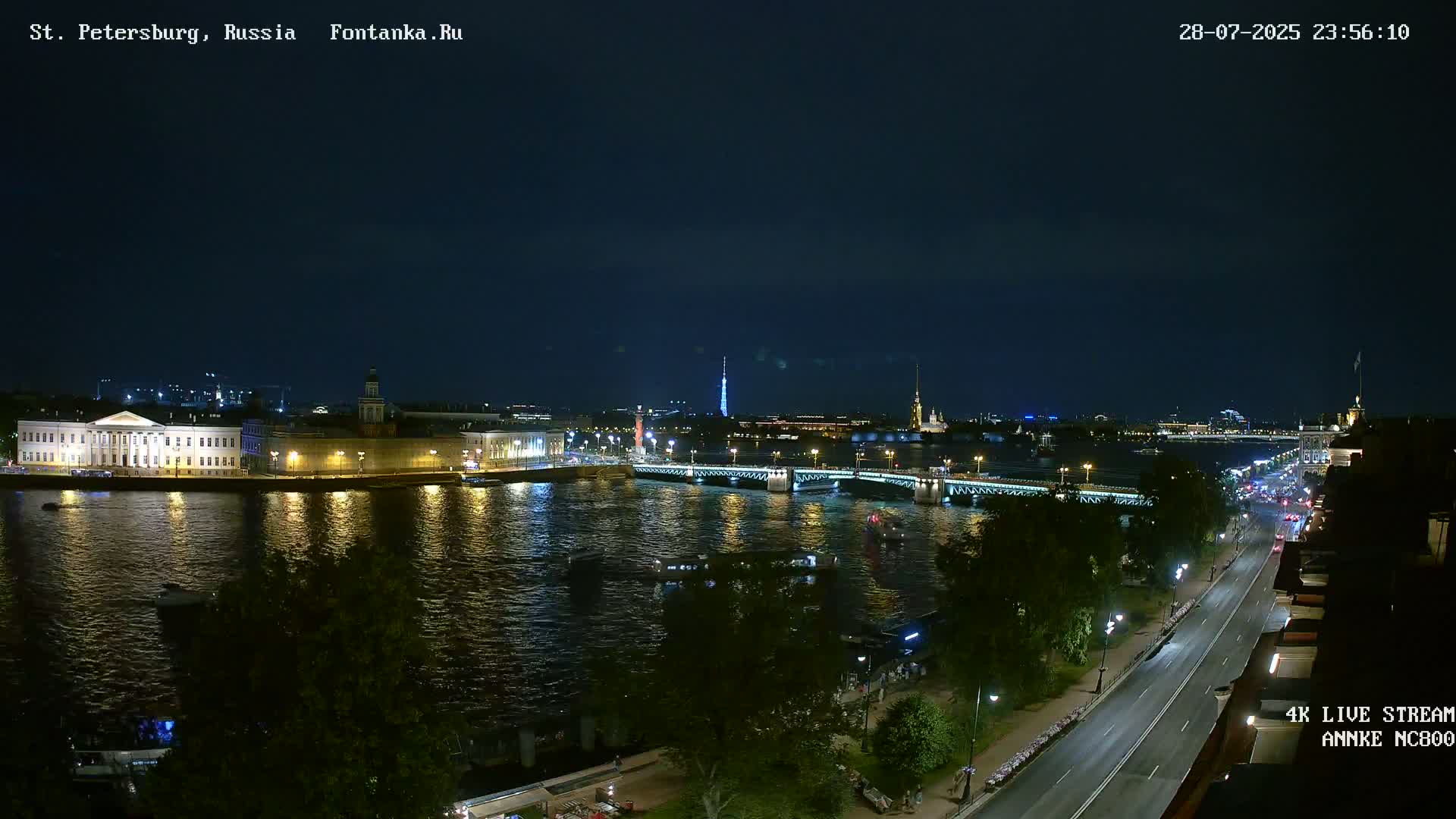 A nighttime view of a city across a river, featuring bridges, buildings, and streetlights under a clear, dark sky.