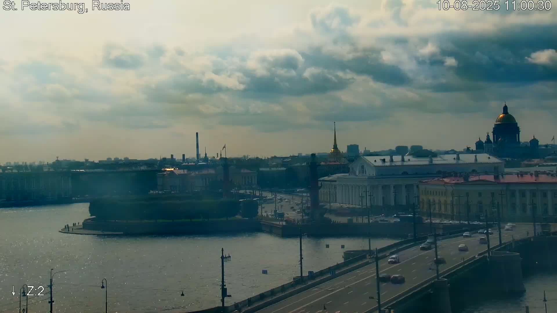 A partly cloudy day reveals a cityscape with a river, bridge, and prominent buildings including a large domed structure.