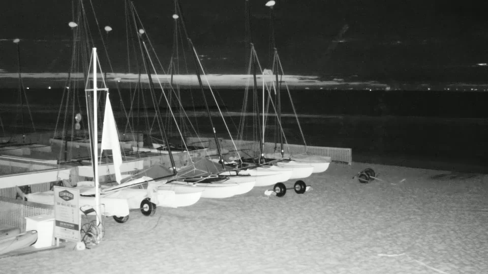 Several small sailboats are beached on a sandy shore at night under a dark sky.