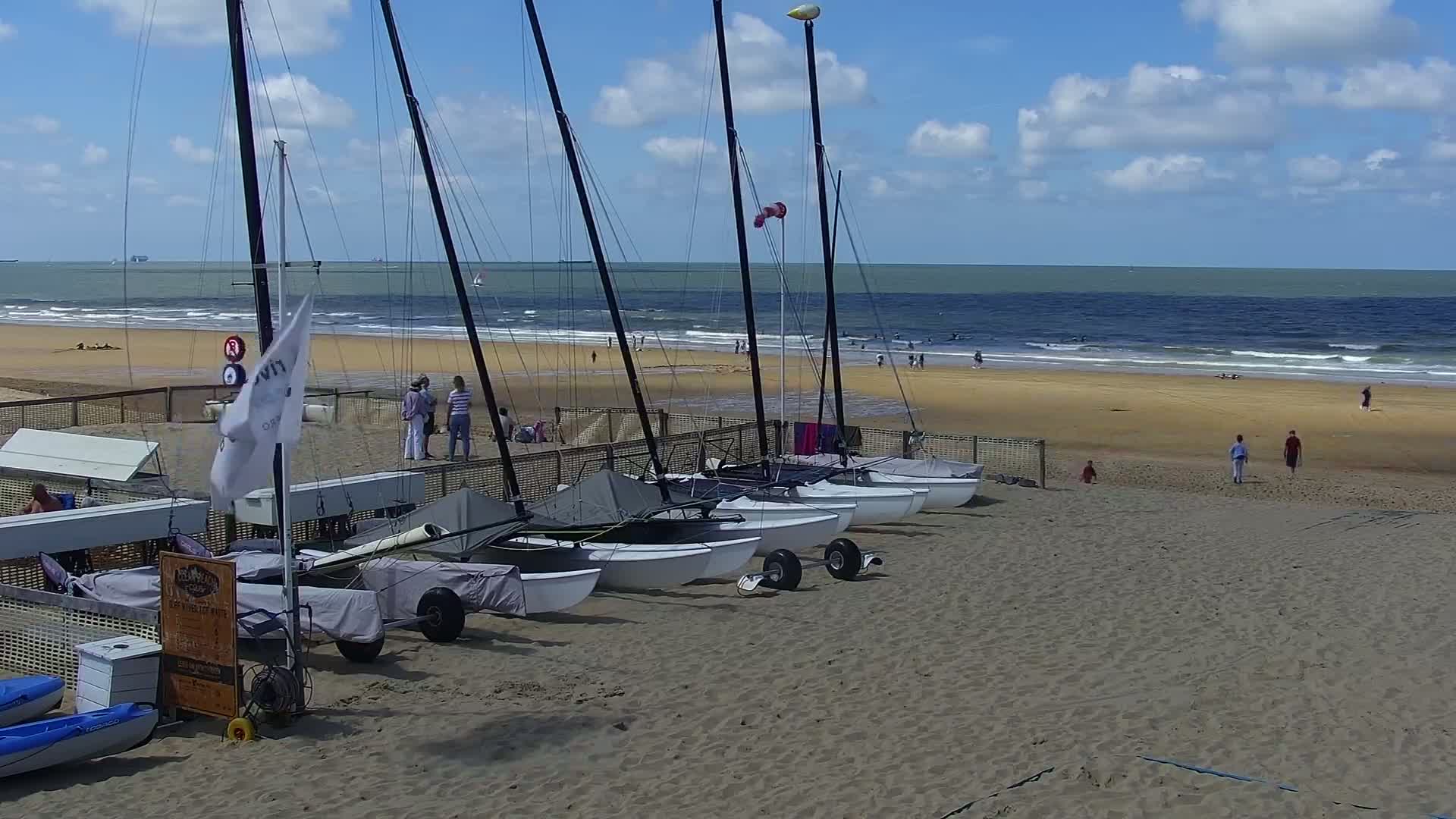 Several small sailboats are beached on a sandy shore at night under a dark sky.