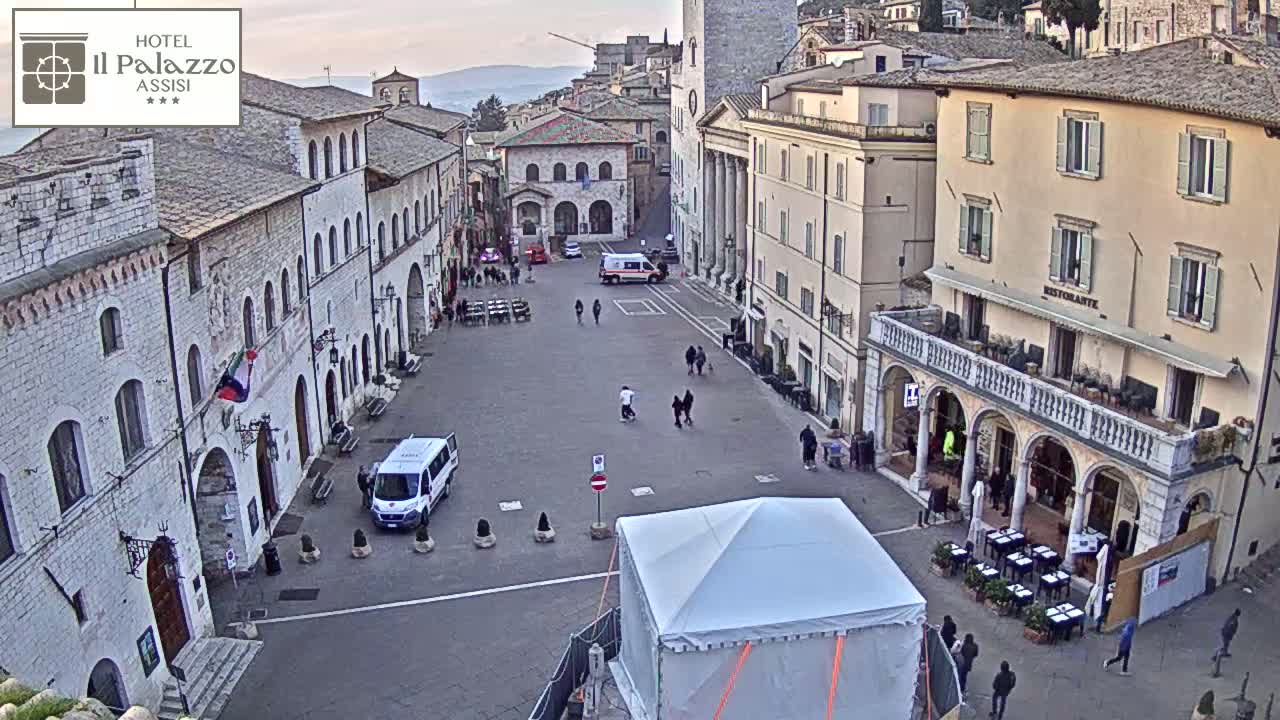 A mostly empty town square in a European city with stone buildings under an overcast sky.