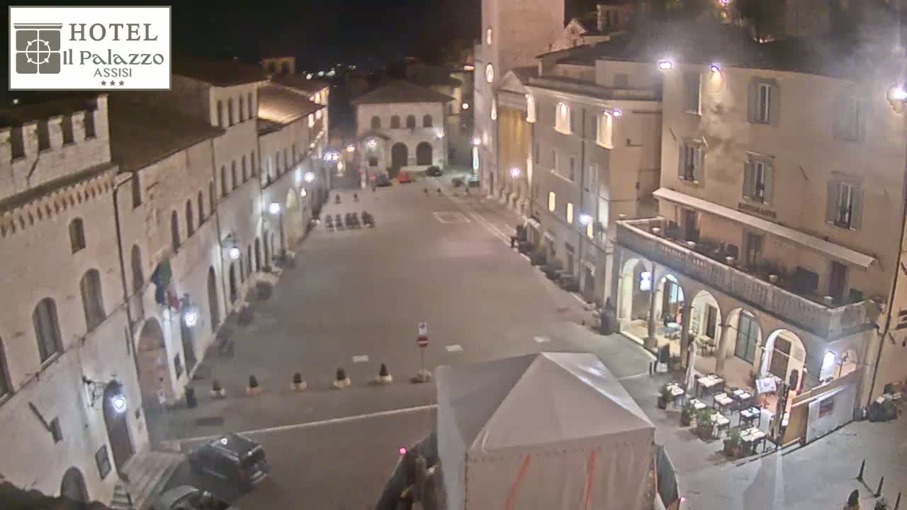 An empty town square at night, surrounded by old stone buildings, under clear skies.