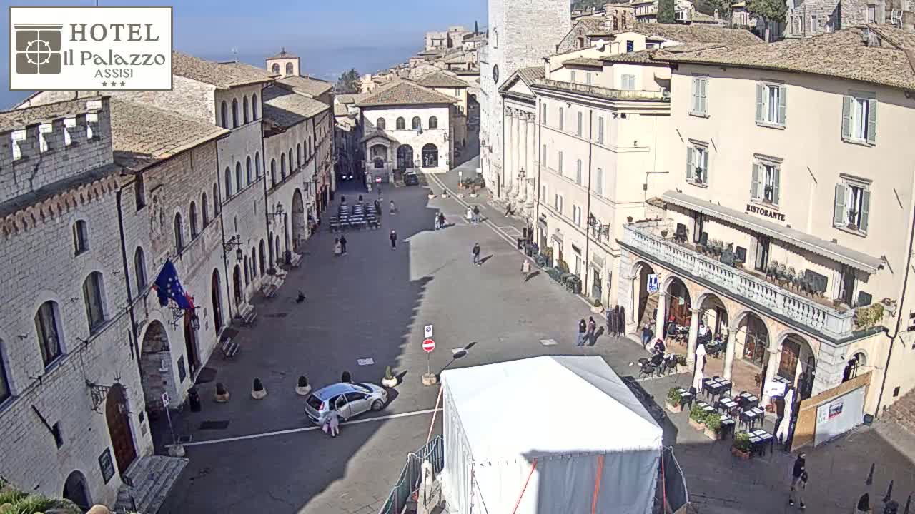 A mostly empty town square, surrounded by historic buildings, on a sunny day.