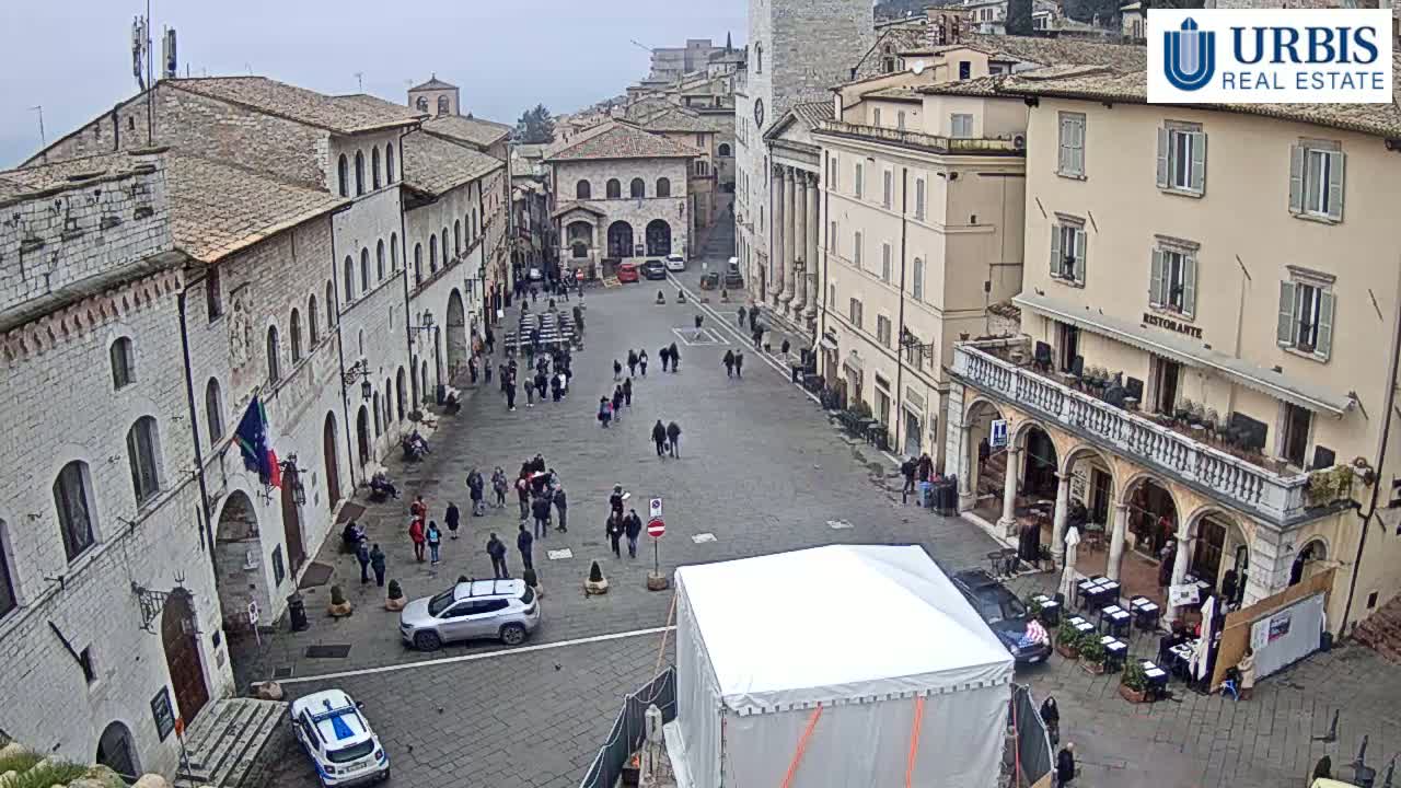 A large, mostly empty town square surrounded by old stone buildings on an overcast day.