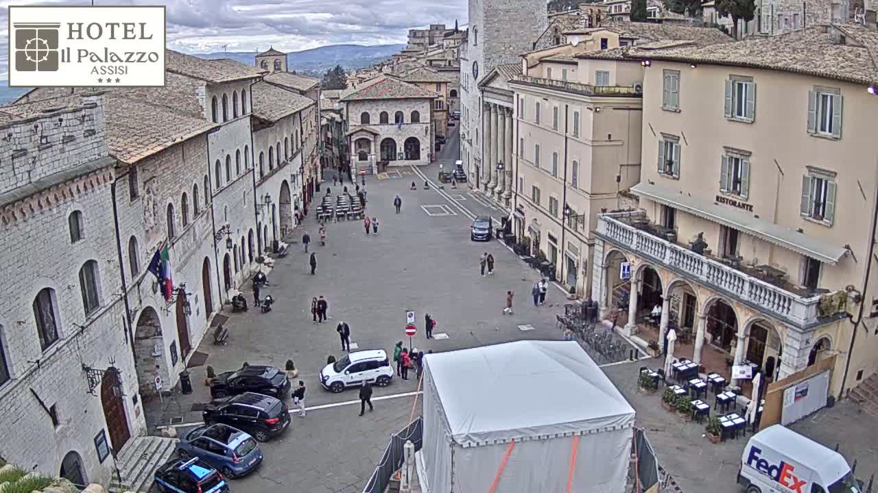 A large, mostly empty town square is surrounded by historic buildings under an overcast sky.