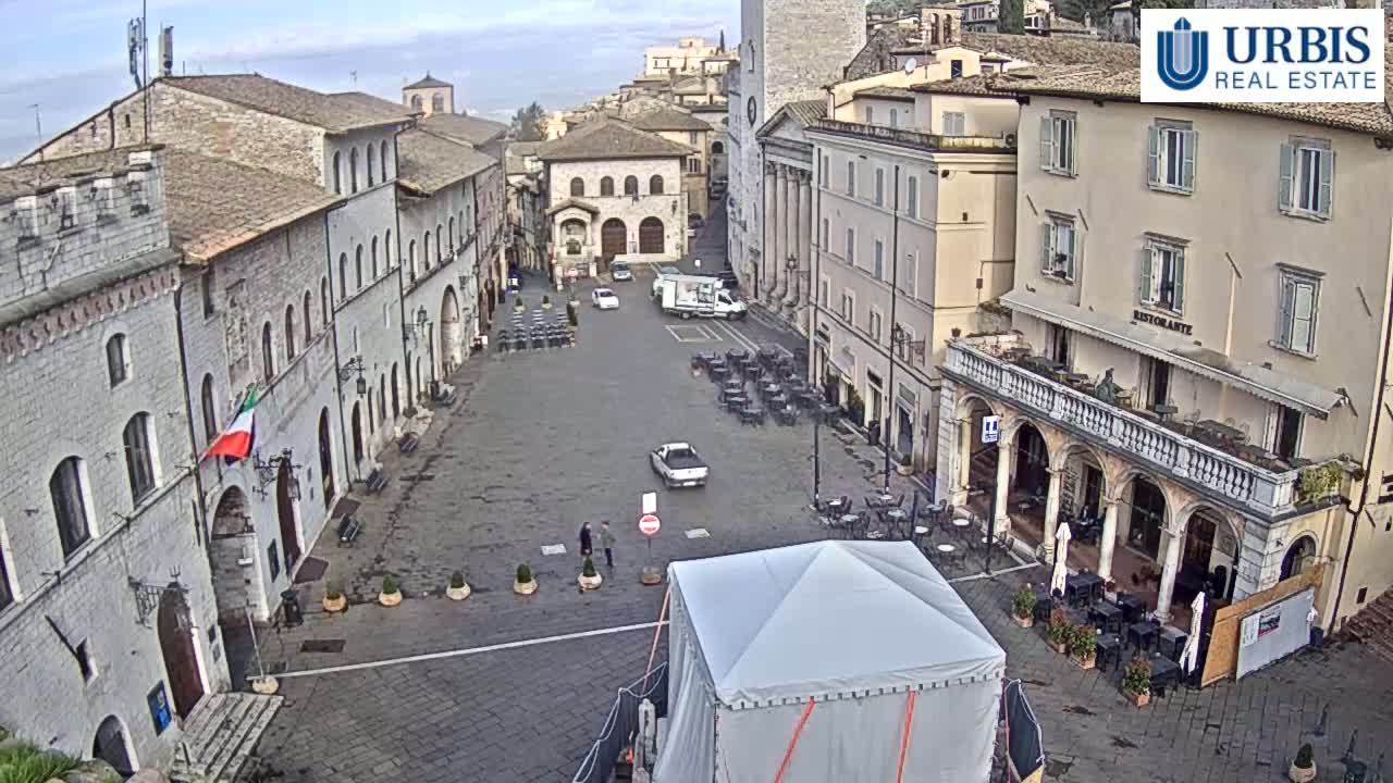 A mostly empty town square with several stone buildings surrounding it, under an overcast sky.