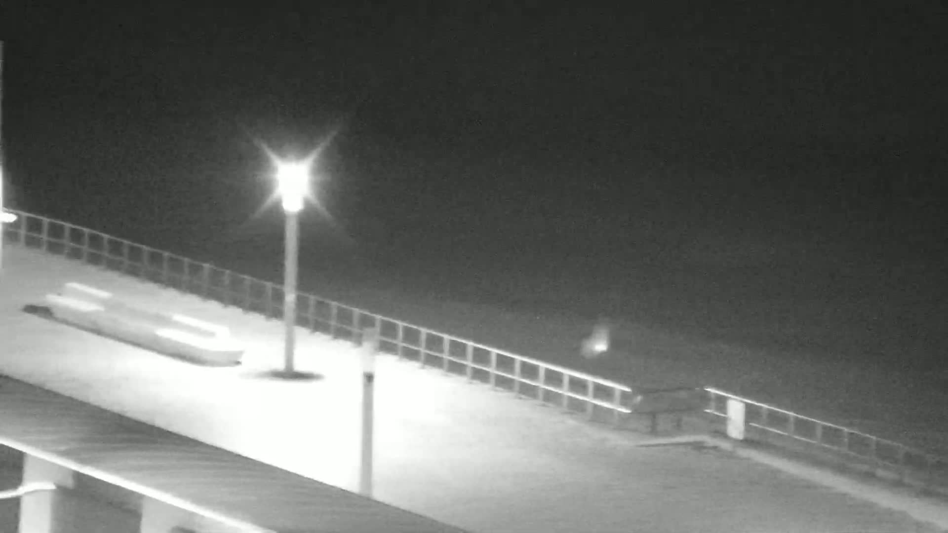 A dark beach at night with several small structures and a few people visible under a clear sky.