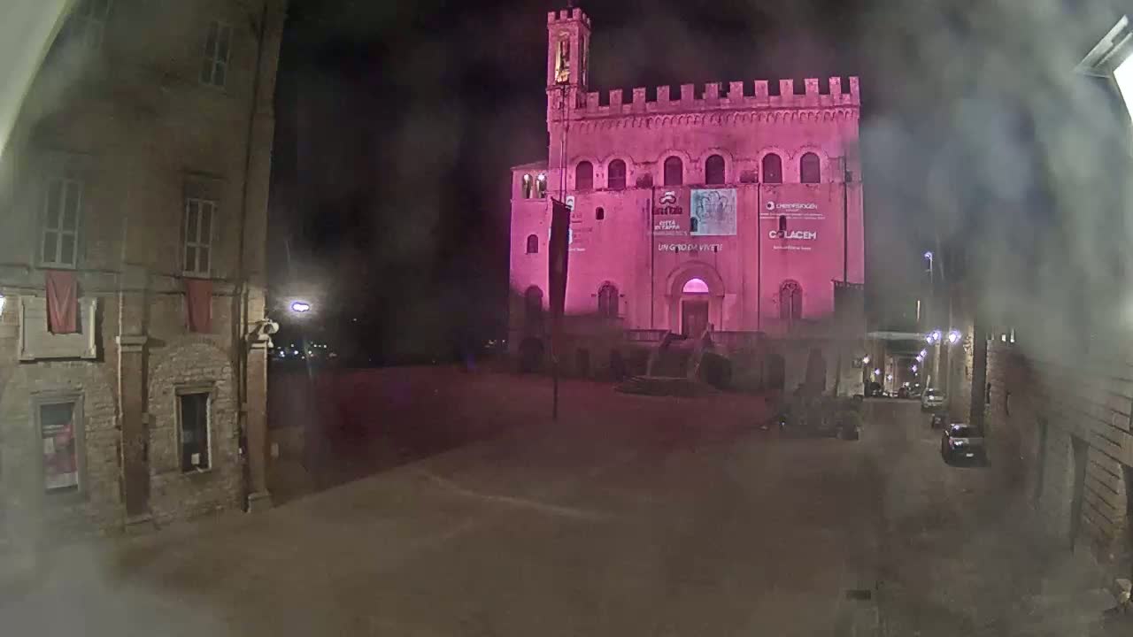 A pink-lit medieval building stands in a dimly lit town square at night, with hazy weather conditions.