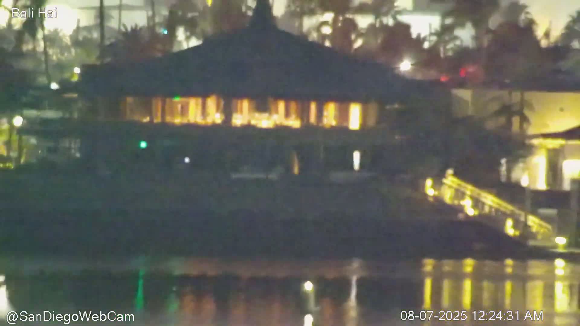 A nighttime view of a brightly lit building near a body of water under a clear sky.