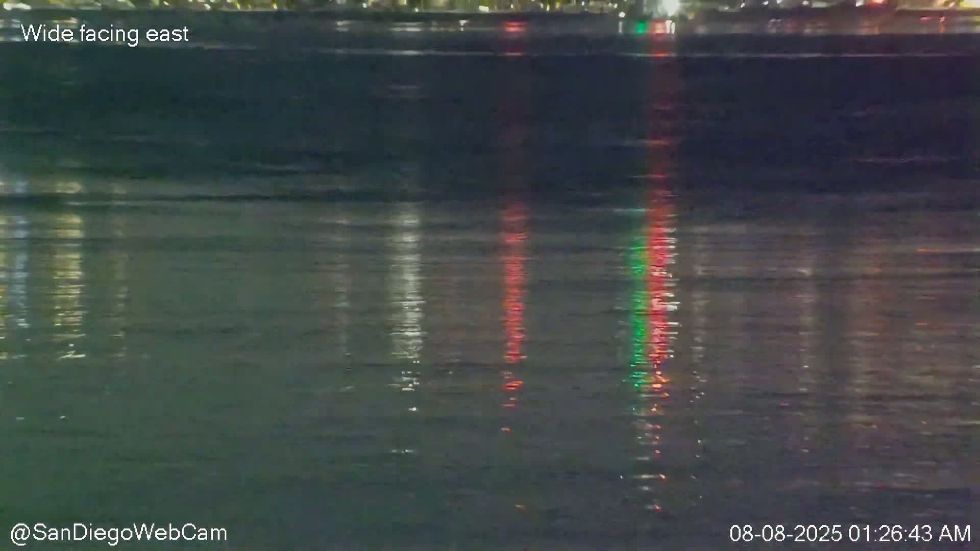 The image shows nighttime reflections of lights on slightly choppy water.
