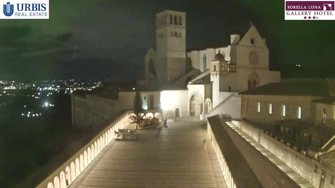 A large, illuminated basilica stands at night, overlooking a city with distant lights, under a dark sky with a faint lightning strike visible in the distance.