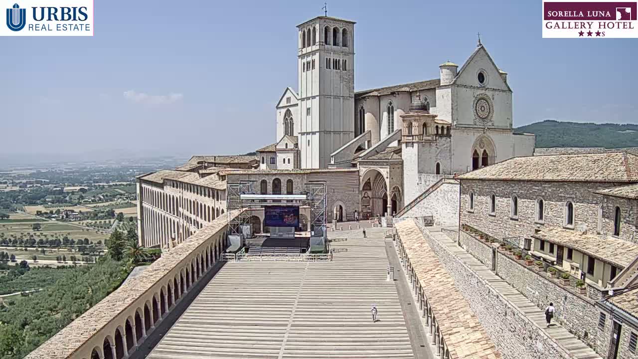 A large stone basilica complex sits atop a hill on a sunny day, overlooking a sprawling landscape.