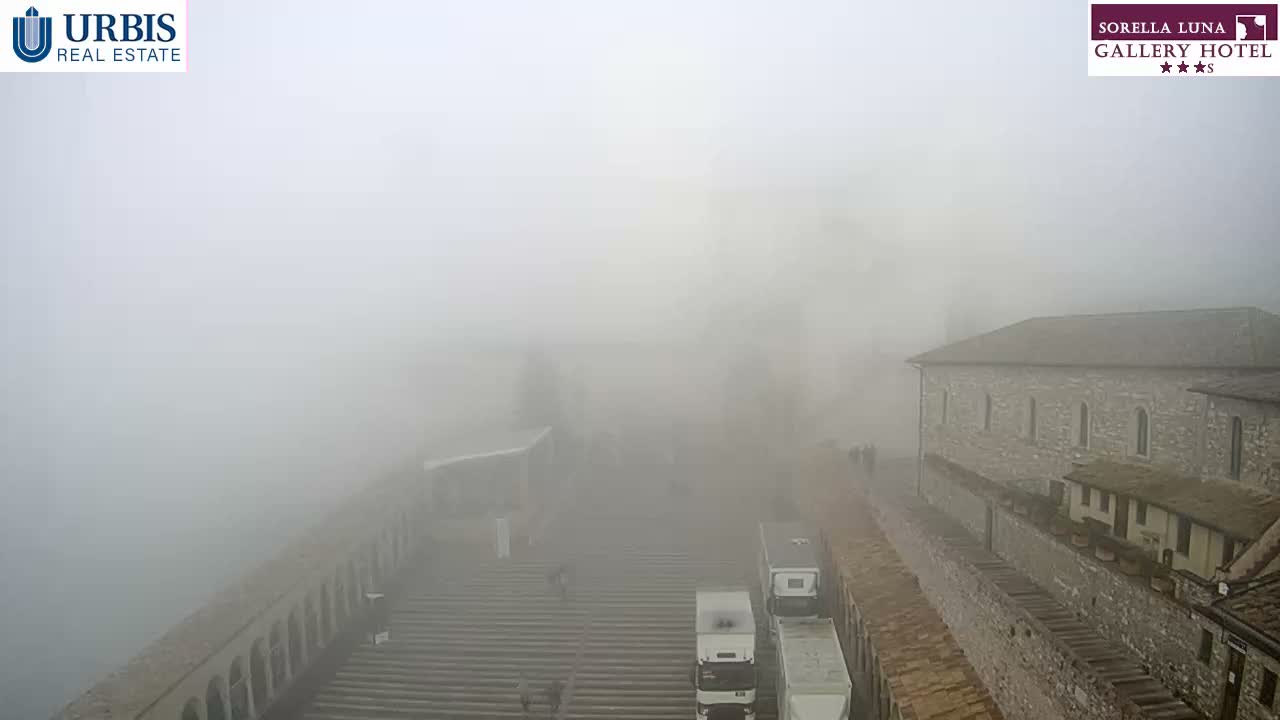 A wide outdoor view shows a large set of stone steps and traditional stone buildings partially obscured by thick fog, with several people visible on the steps.
