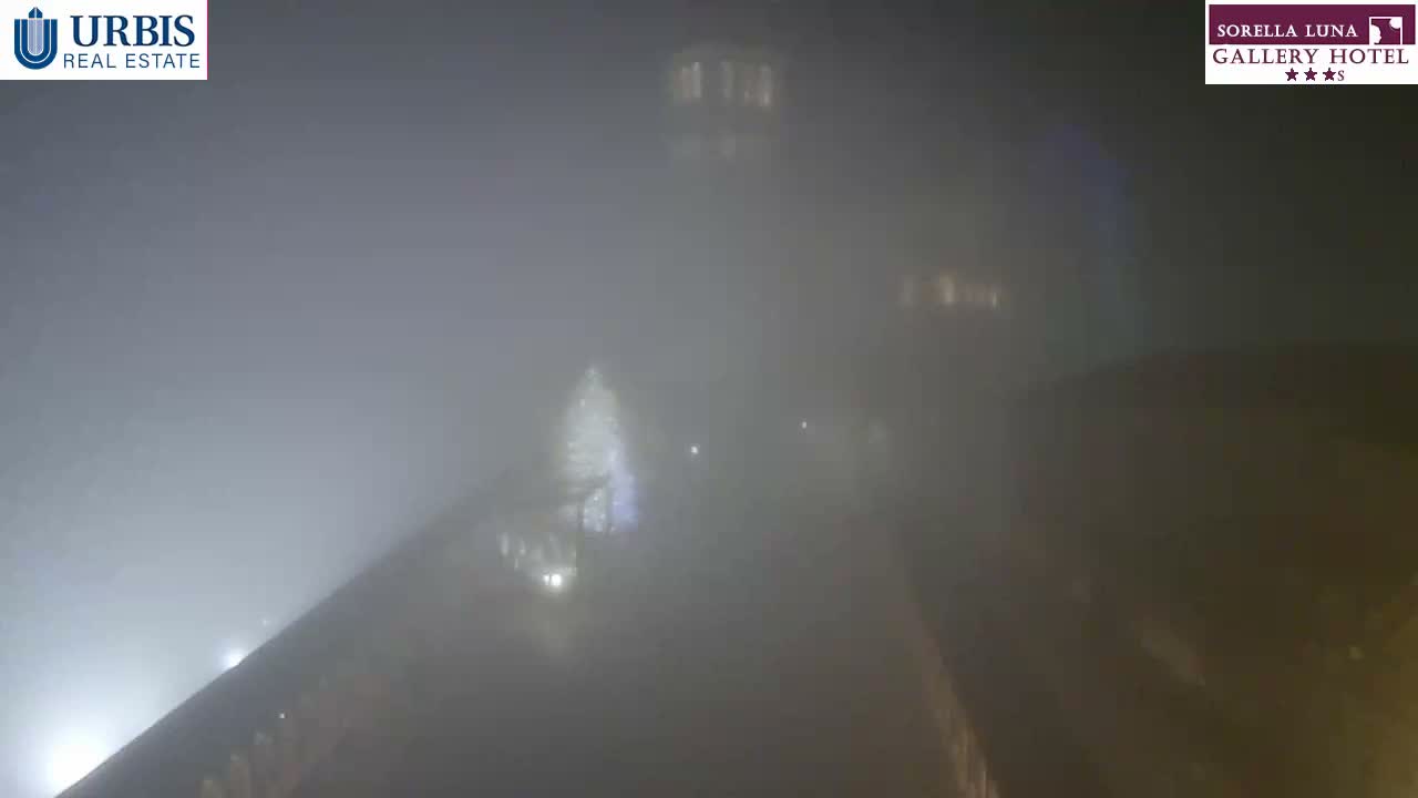 A wide outdoor view shows a large set of stone steps and traditional stone buildings partially obscured by thick fog, with several people visible on the steps.