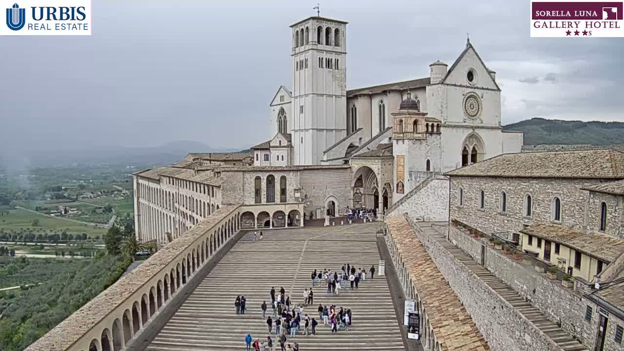 A wide outdoor view shows a large set of stone steps and traditional stone buildings partially obscured by thick fog, with several people visible on the steps.