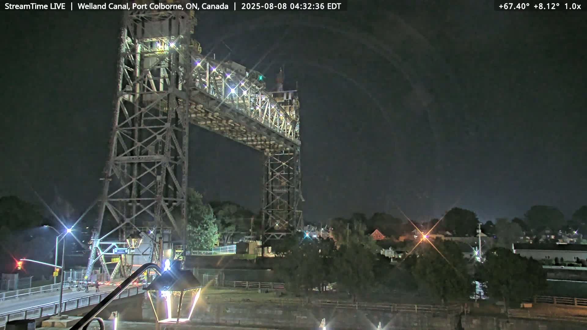 A large metal lift bridge stands tall at night under a dark sky.
