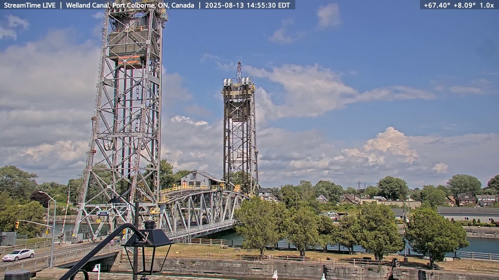A metal lift bridge spans a waterway under a partly cloudy sky.