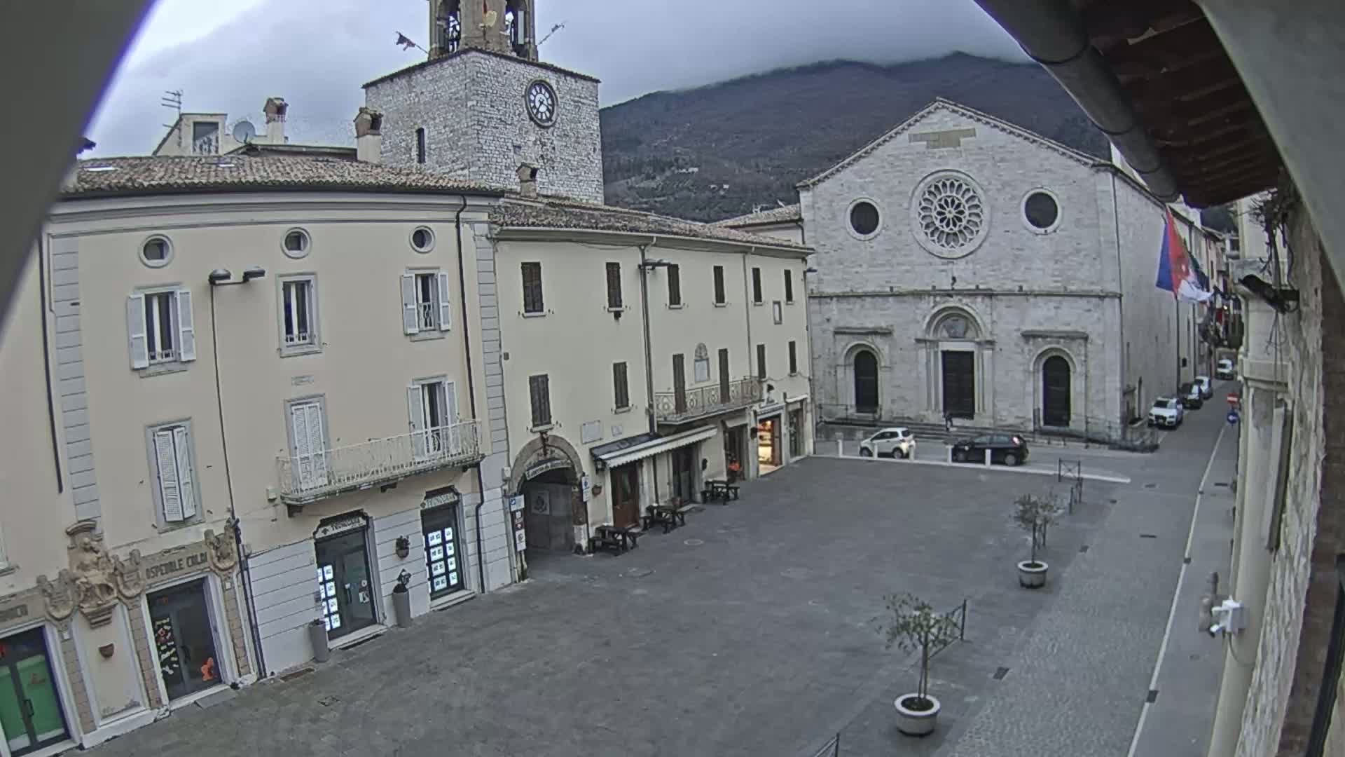 A town square with several buildings, including a clock tower and a church with a rose window, is visible under an overcast sky.