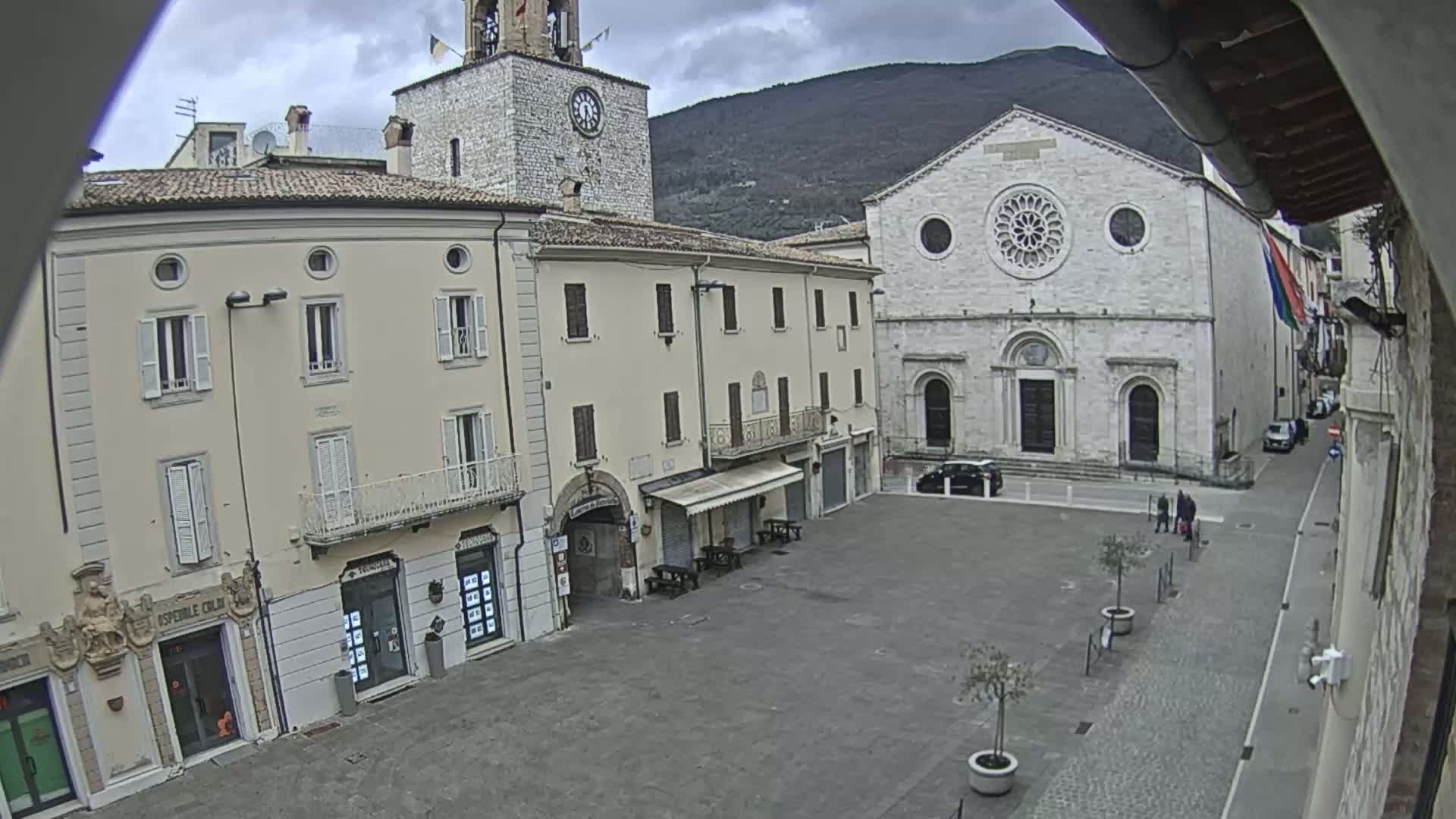 A town square with several buildings, including a church with a rose window and a clock tower, is visible under an overcast sky.