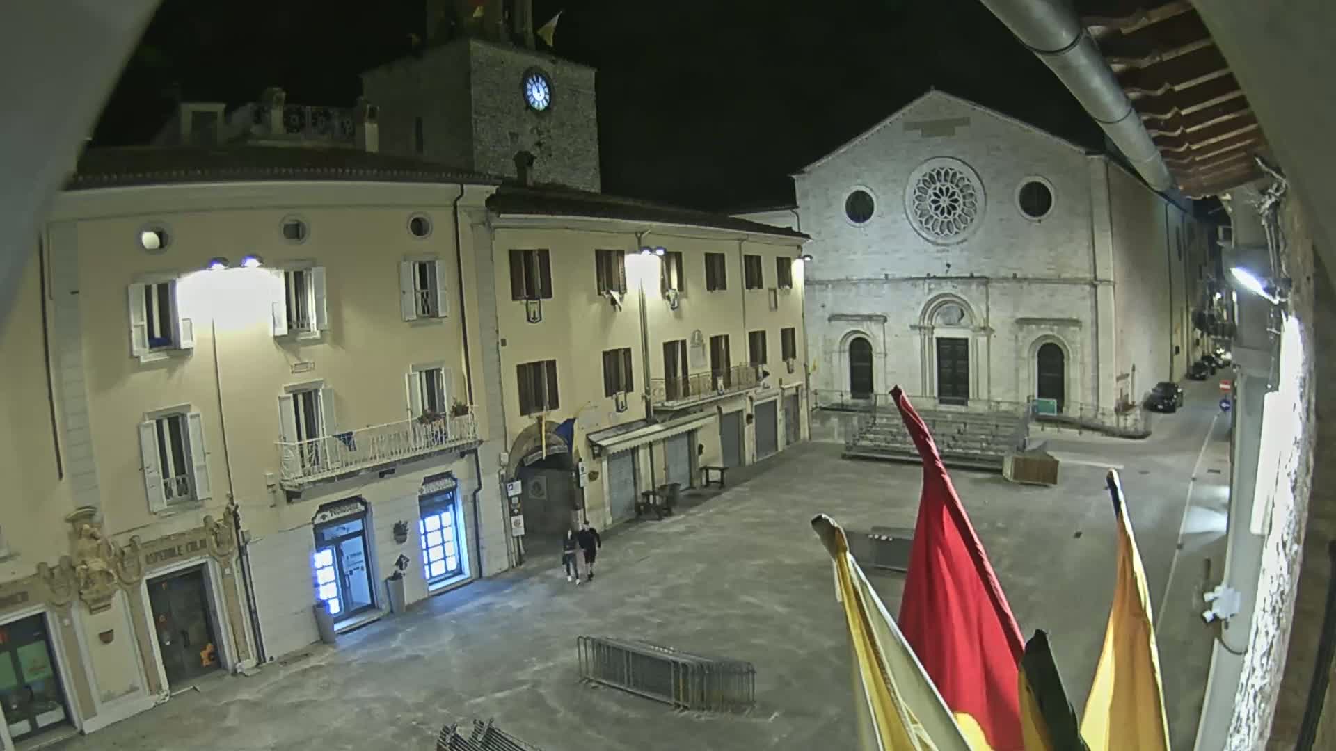 A nighttime view of a town square with several buildings, including a church with a rose window, under clear skies.